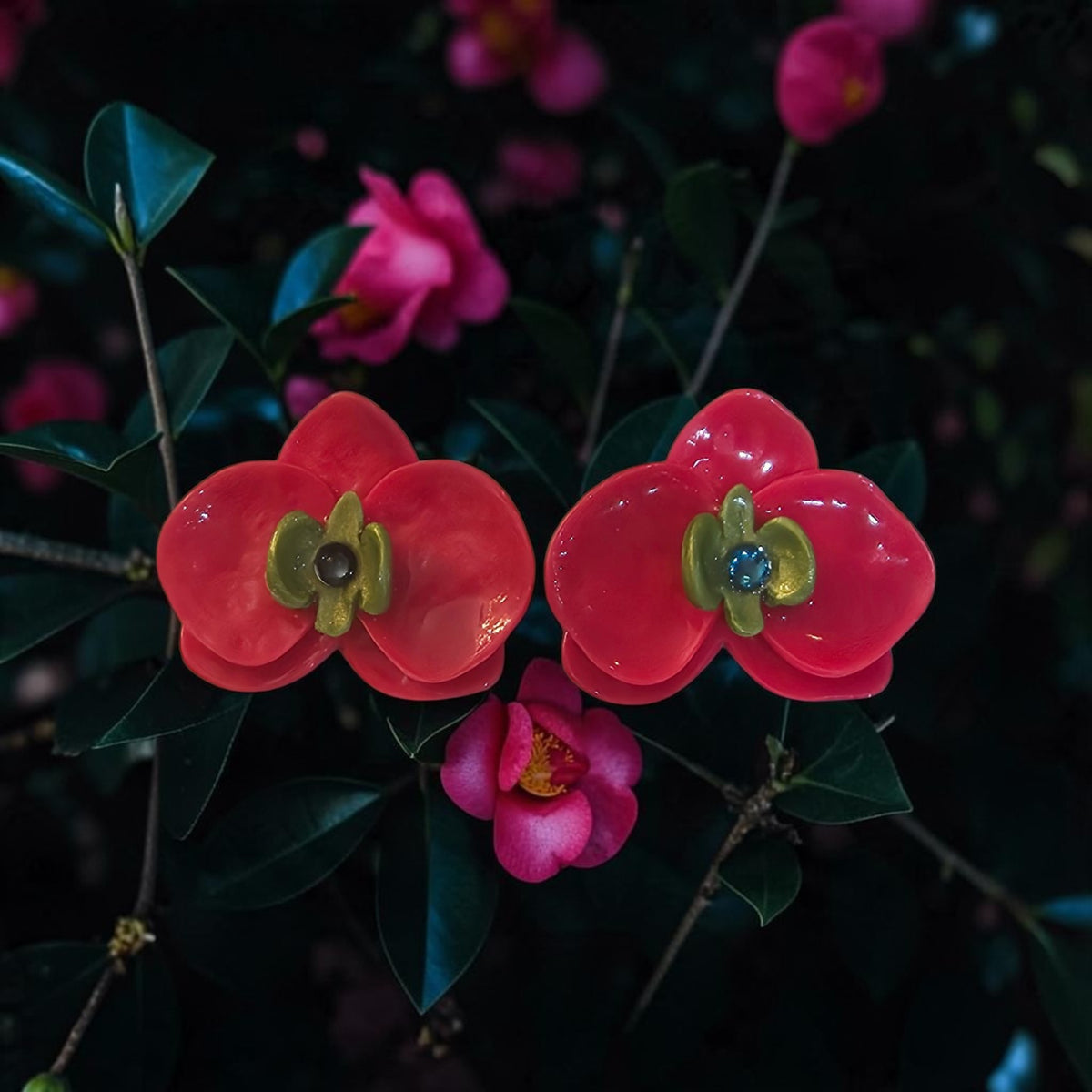 Pink orchid-inspired polymer clay stud earrings with green centers and a glossy resin finish