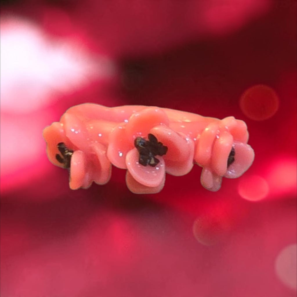 Glossy pink ring with two sculpted pink flowers and dark sparkling centers