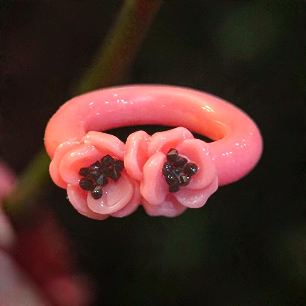 Glossy pink ring with three sculpted pink flowers and dark sparkling centers