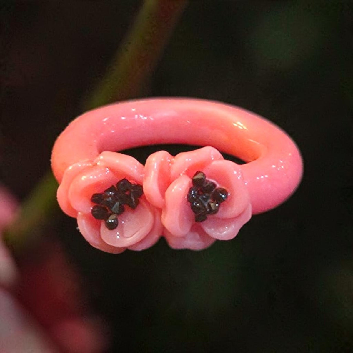 Glossy pink ring with three sculpted pink flowers and dark sparkling centers