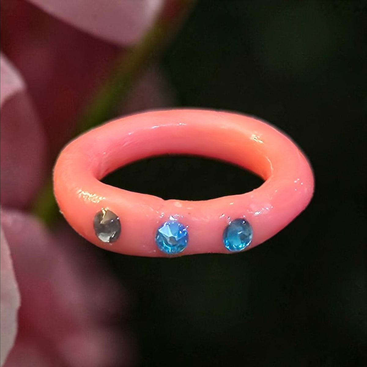 Glossy pink band ring with three blue and smoky-toned faceted accents