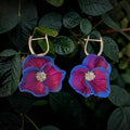 Magenta polymer clay flower earrings with blue-edged petals, sparkling silver-tone centers, and silver-tone hoops